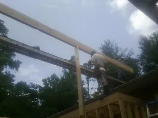 Carpenter setting a ridge beam over a new addition frame — Ice Dam Removal by Roofing Brothers in Center Hill