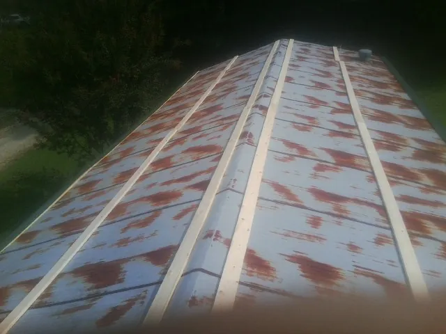 Rusted metal roof panels with new wood purlins before replacement — Storm Damage Roof Repair in Center Hill by Roofing Brothers