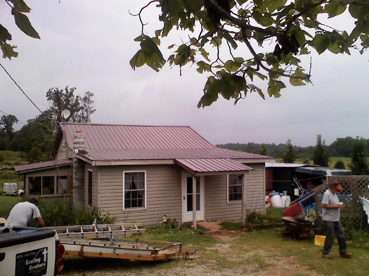 Crew finishing a mauve metal roof on a small farmhouse in Center Hill