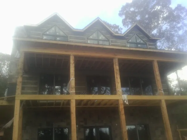 Dormers and porch framing on a large log home under construction — Roof Coating work by our crew in Center Hill