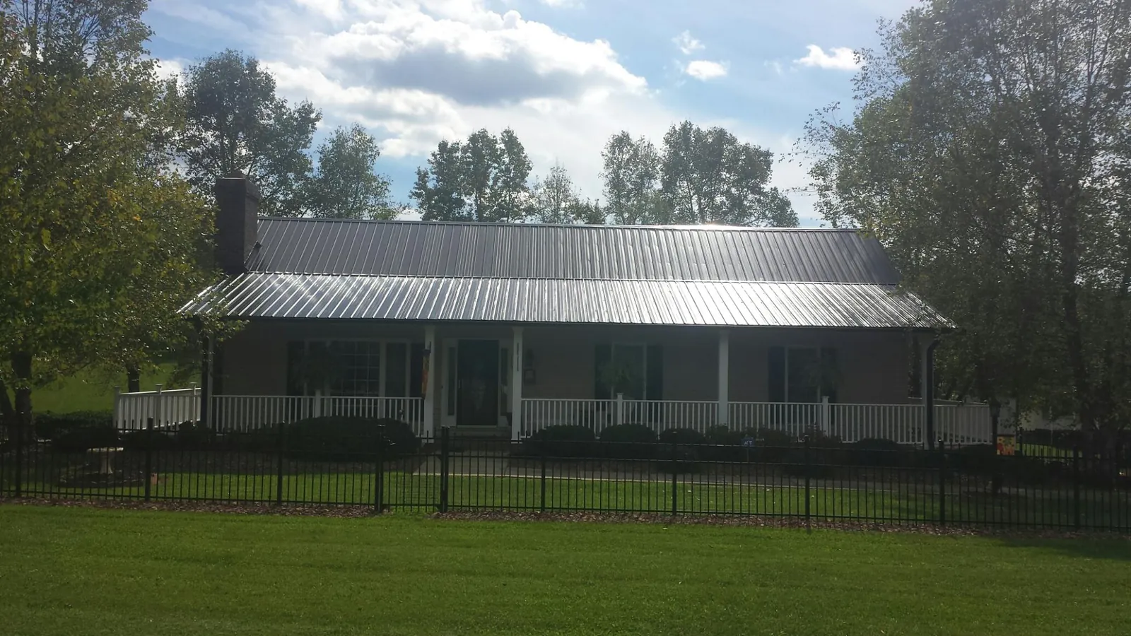 Gray metal roof on a brick ranch with a full width front porch — Gutter Guard Installation work by our crew in Center Hill