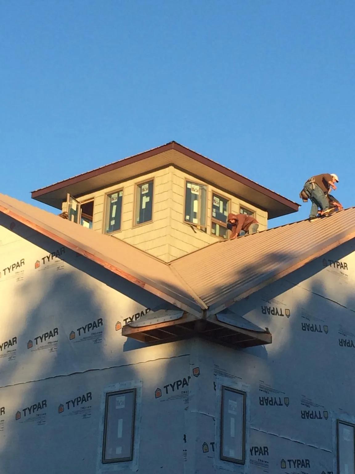 Roofers working around a rooftop cupola on a new metal roof at sunset — Roof Waterproofing in Center Hill by Roofing Brothers